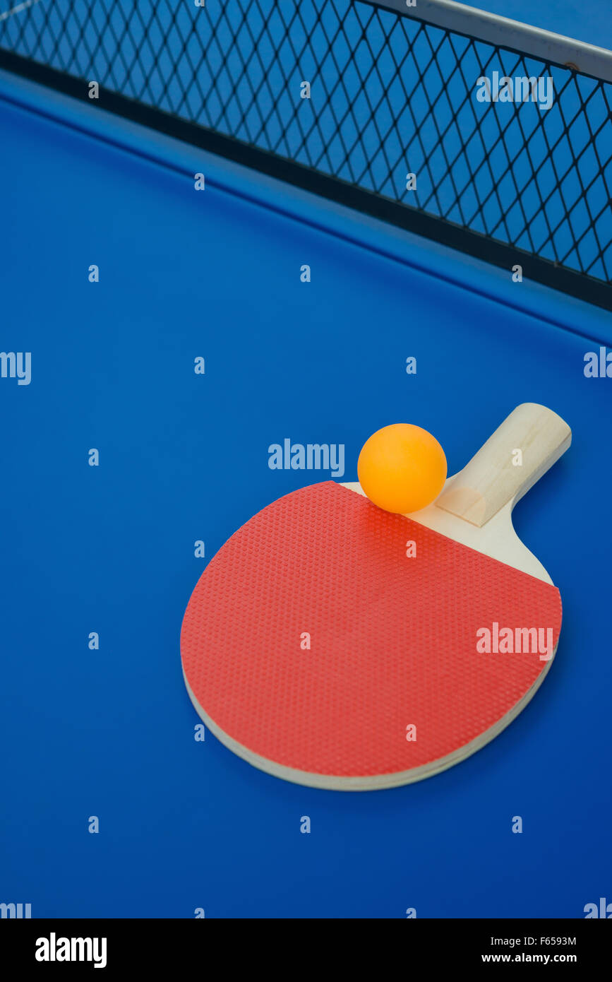 pingpong racket and ball and net on a blue pingpong table vertical Stock Photo