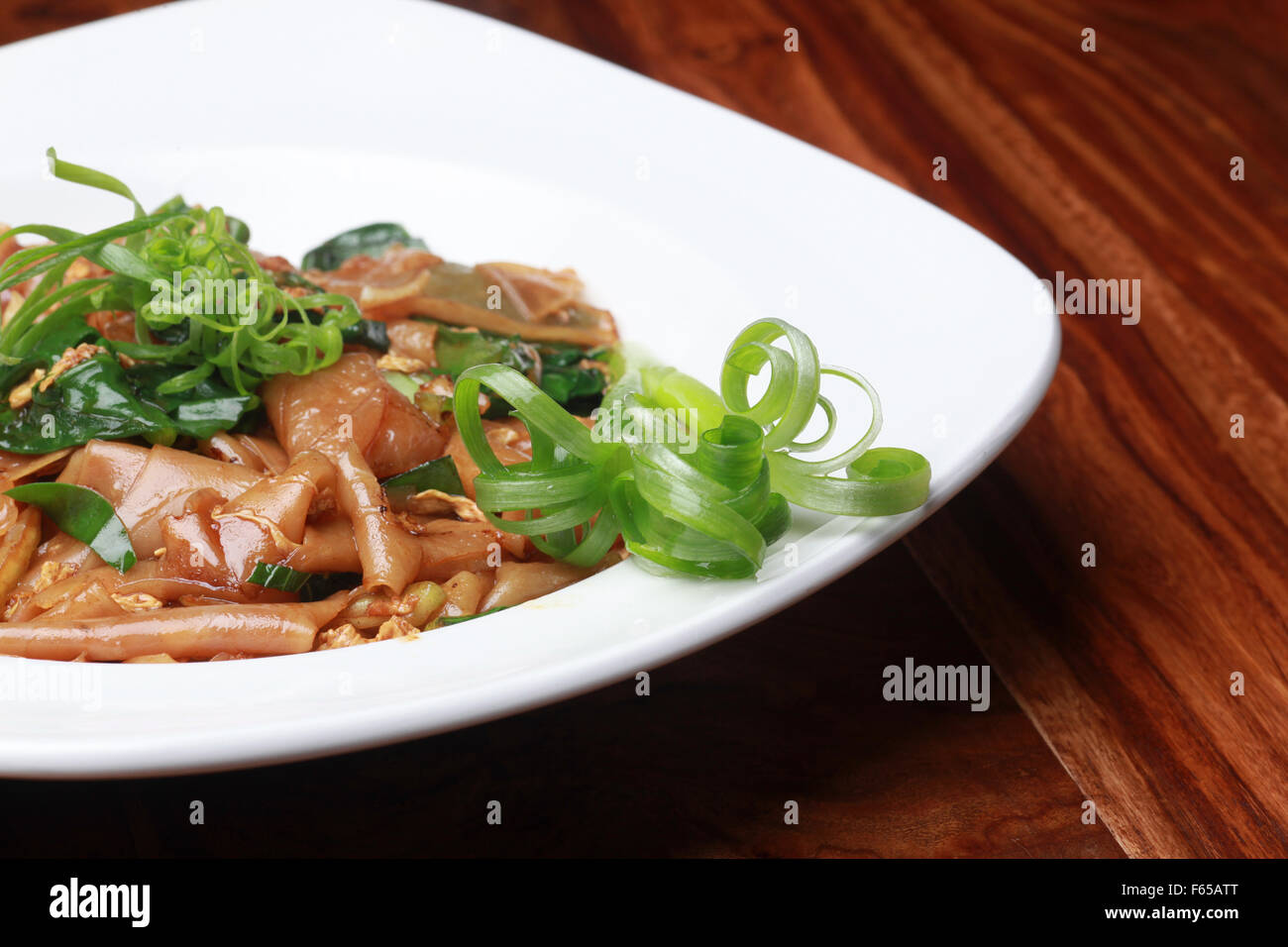 Vegetarian Stir fried noodles garnished with greens Stock Photo