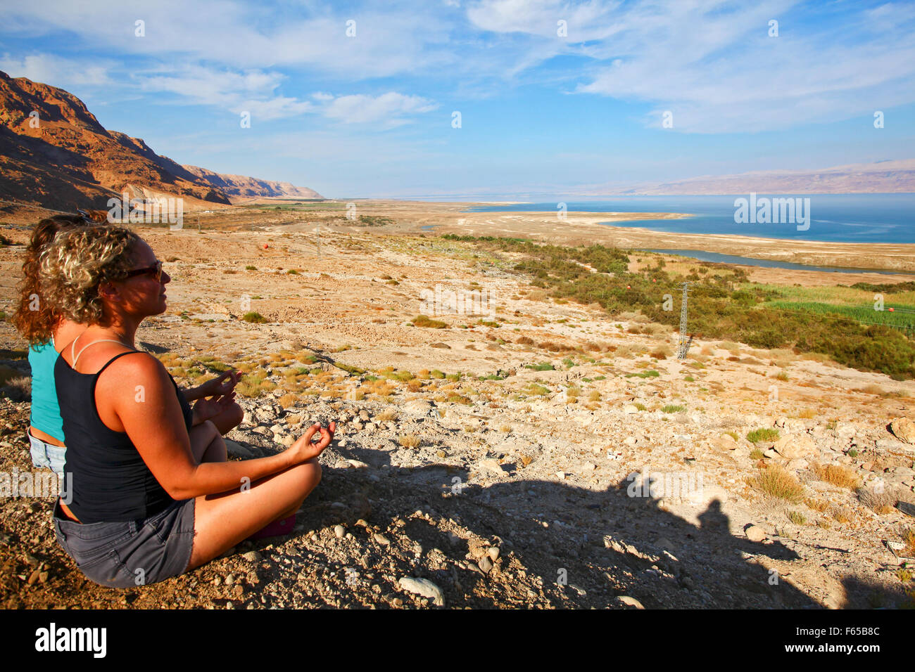 2 young women meditate in the desert Stock Photo