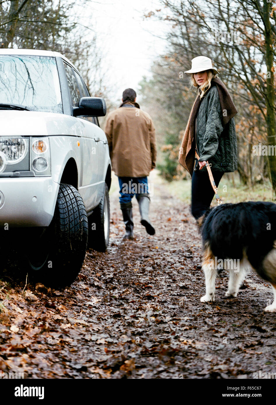 Couple goes for a walk in the forest with their pet dog Stock Photo - Alamy