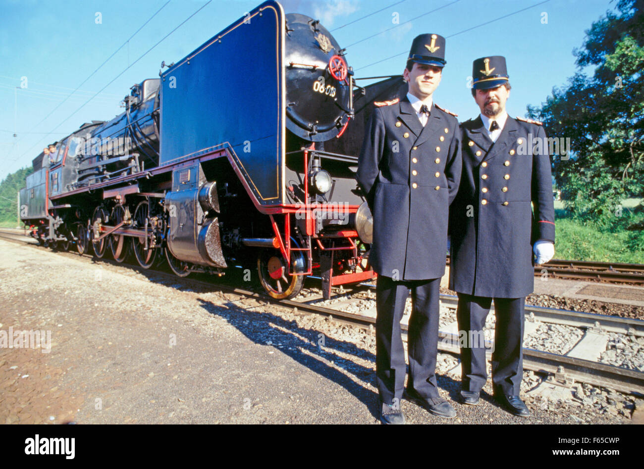 Two conductors wearing uniforms standing in front of museum train