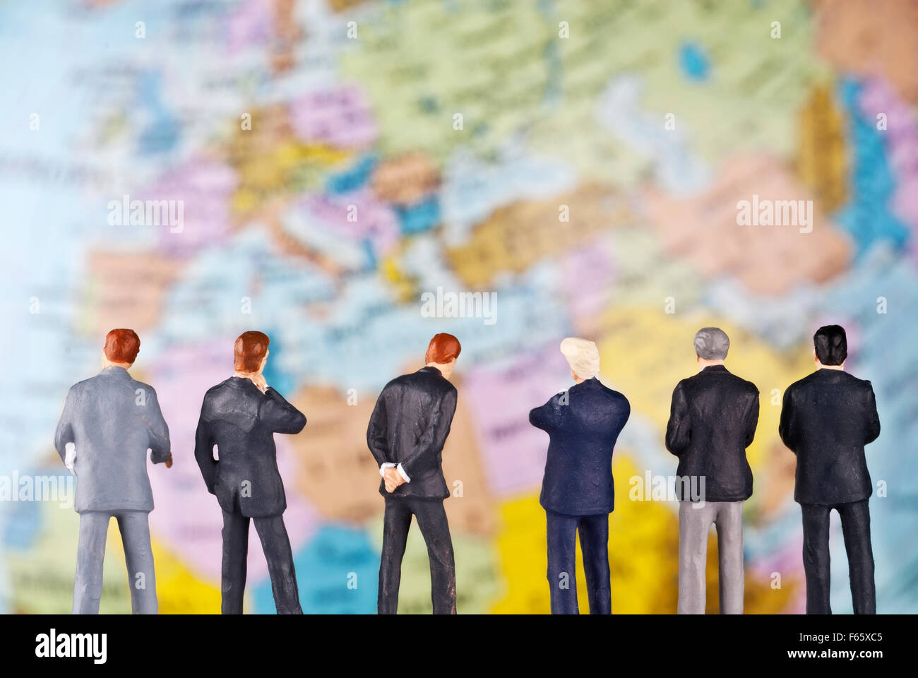 Businessmen as toy figures in front of a globe. Stock Photo