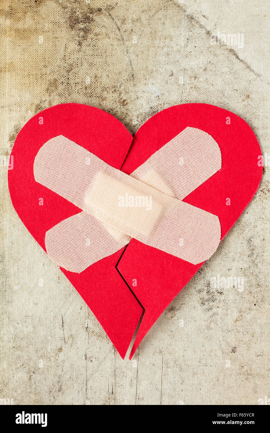 Broken heart with plaster on the dirty background Stock Photo