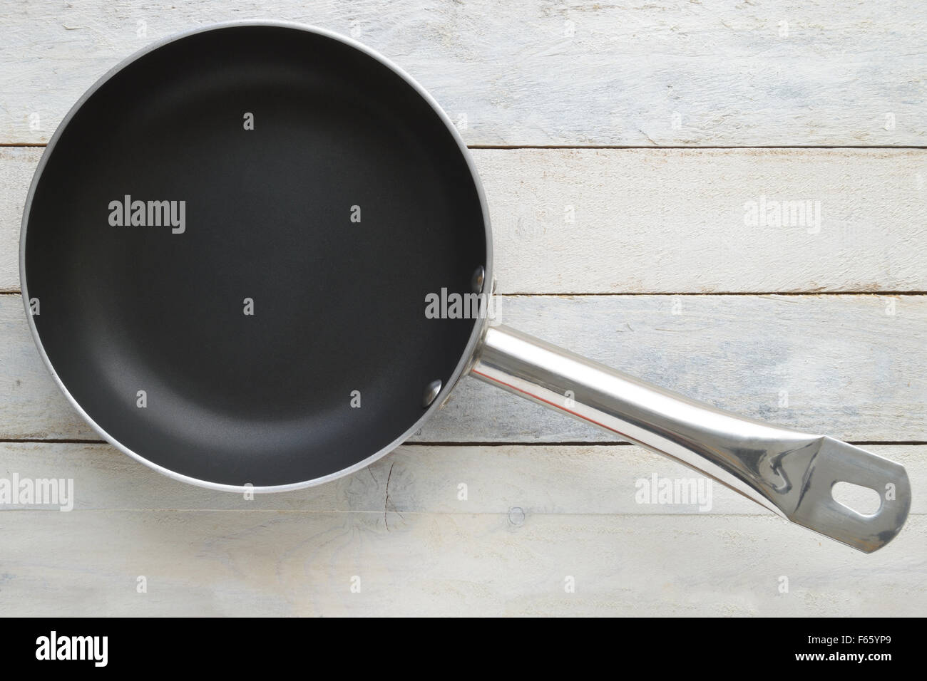 Frying pan on a white wooden table. Top view. Empty copy space for editor's text. Stock Photo