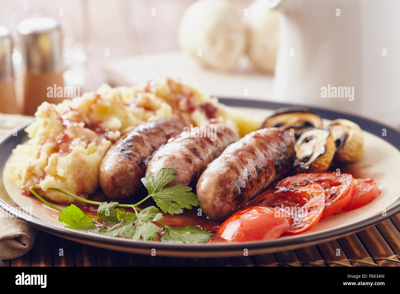 Sausage and mash dish with grilled mushrooms and tomatoes Stock Photo