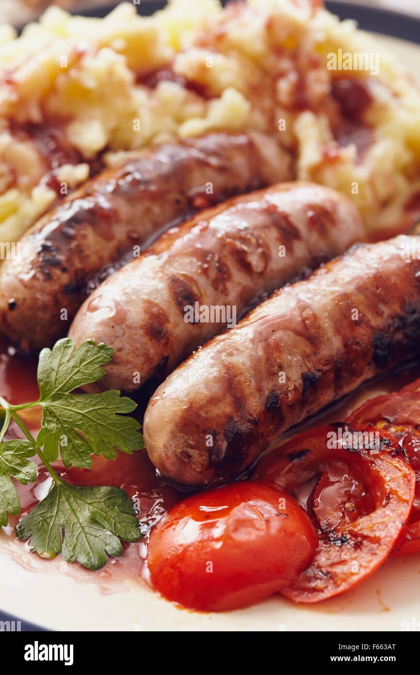 Sausage and mash dish with grilled mushrooms and tomatoes Stock Photo