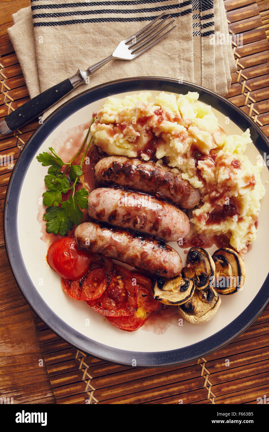 Sausage and mash dish with grilled mushrooms and tomatoes Stock Photo