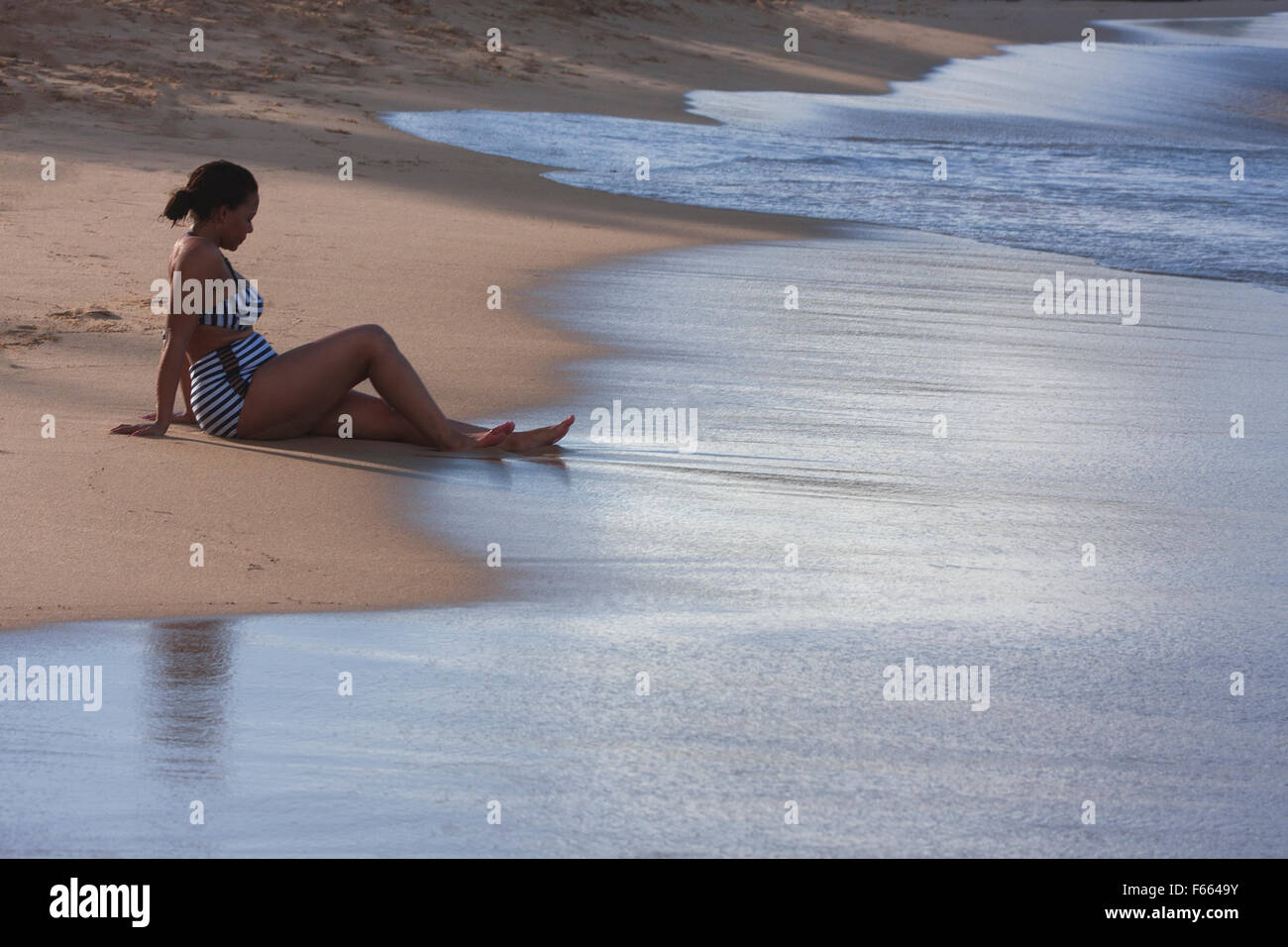 Women relaxing on a beach deep in thought. Stock Photo