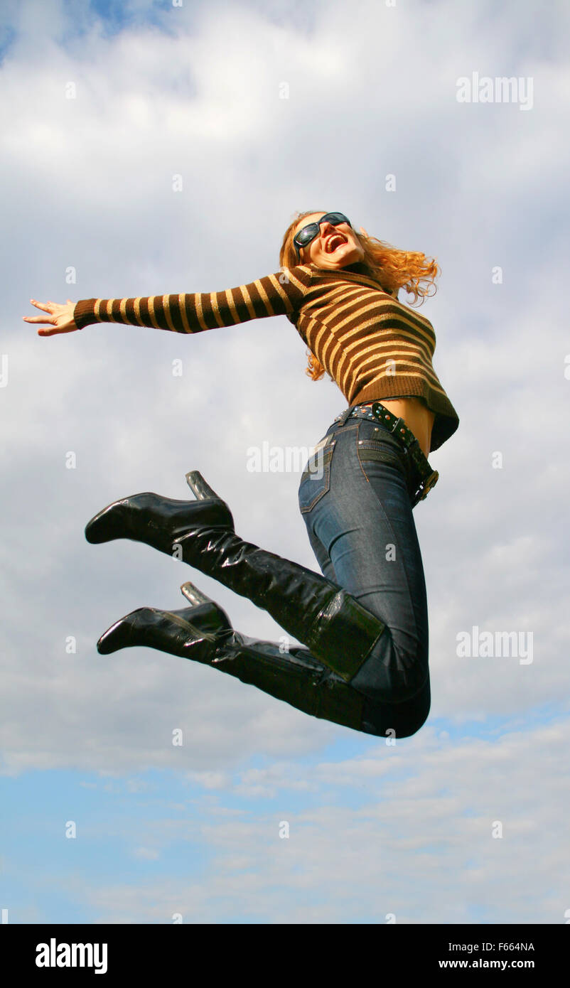 Playful woman jumping at blue cloudy sky Stock Photo - Alamy