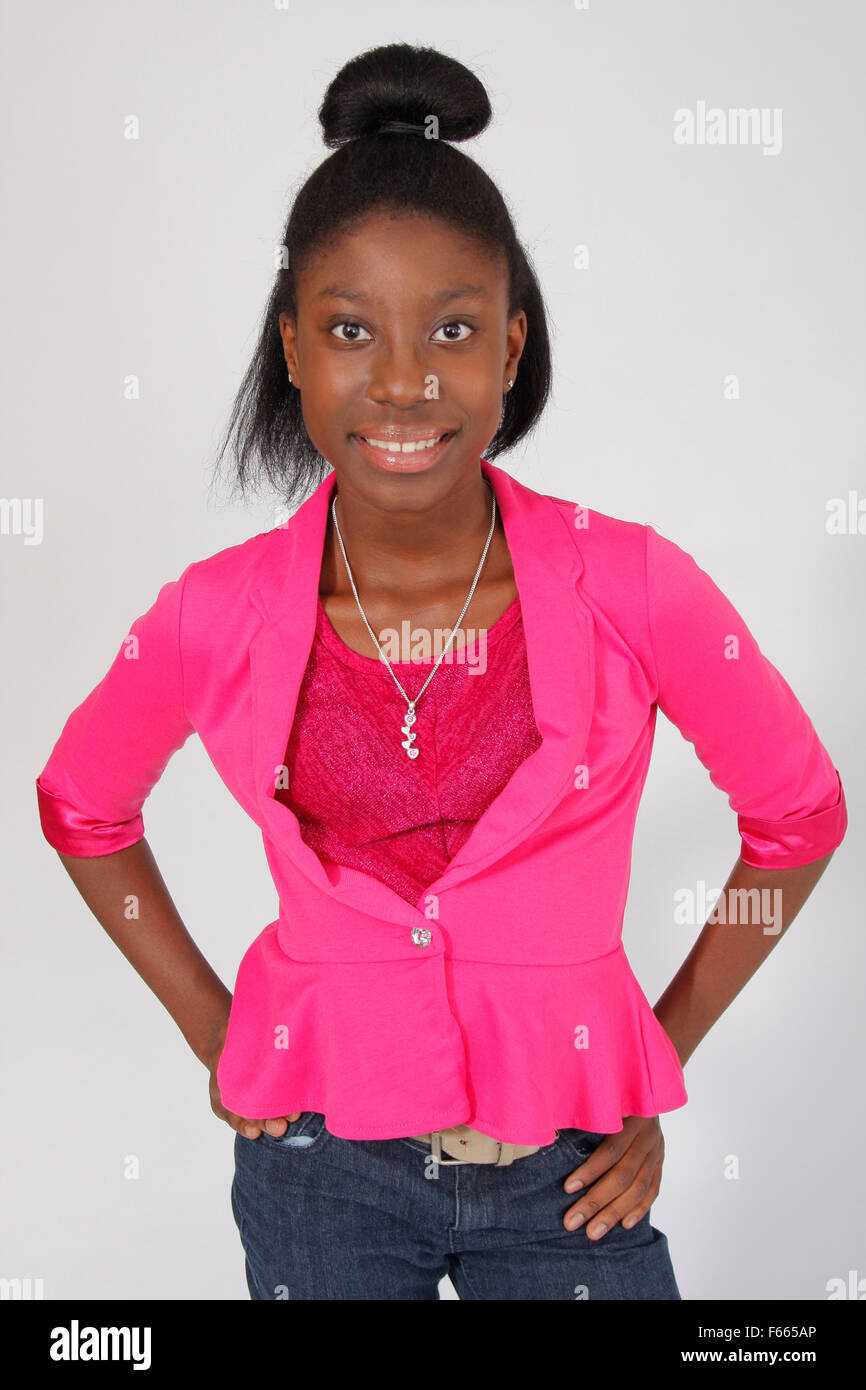 Portrait of a young African American girl wearing a pink shirt and jeans on a white backdrop. Stock Photo
