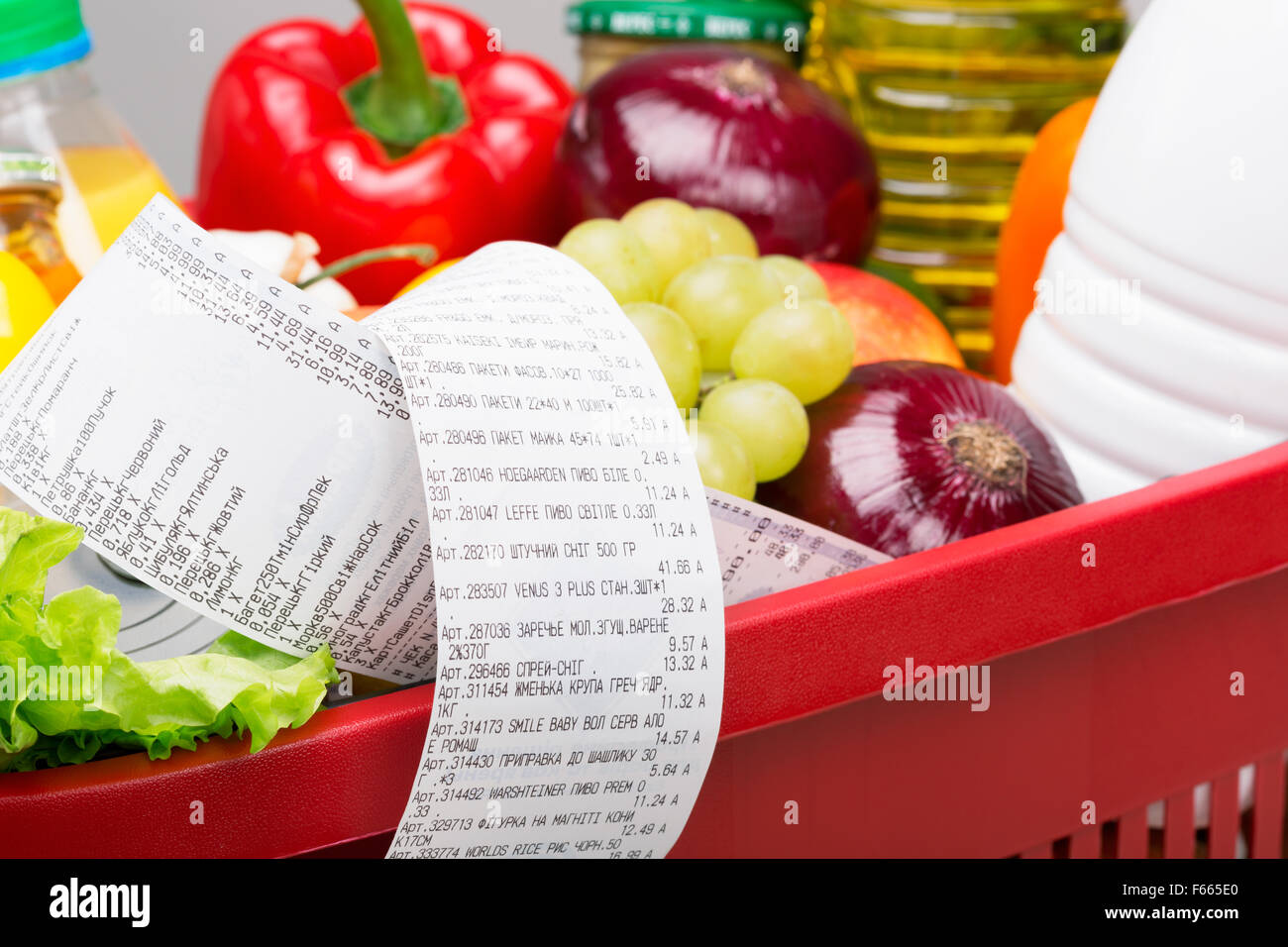 Red basket full of goods. Very long cashier's check. Stock Photo