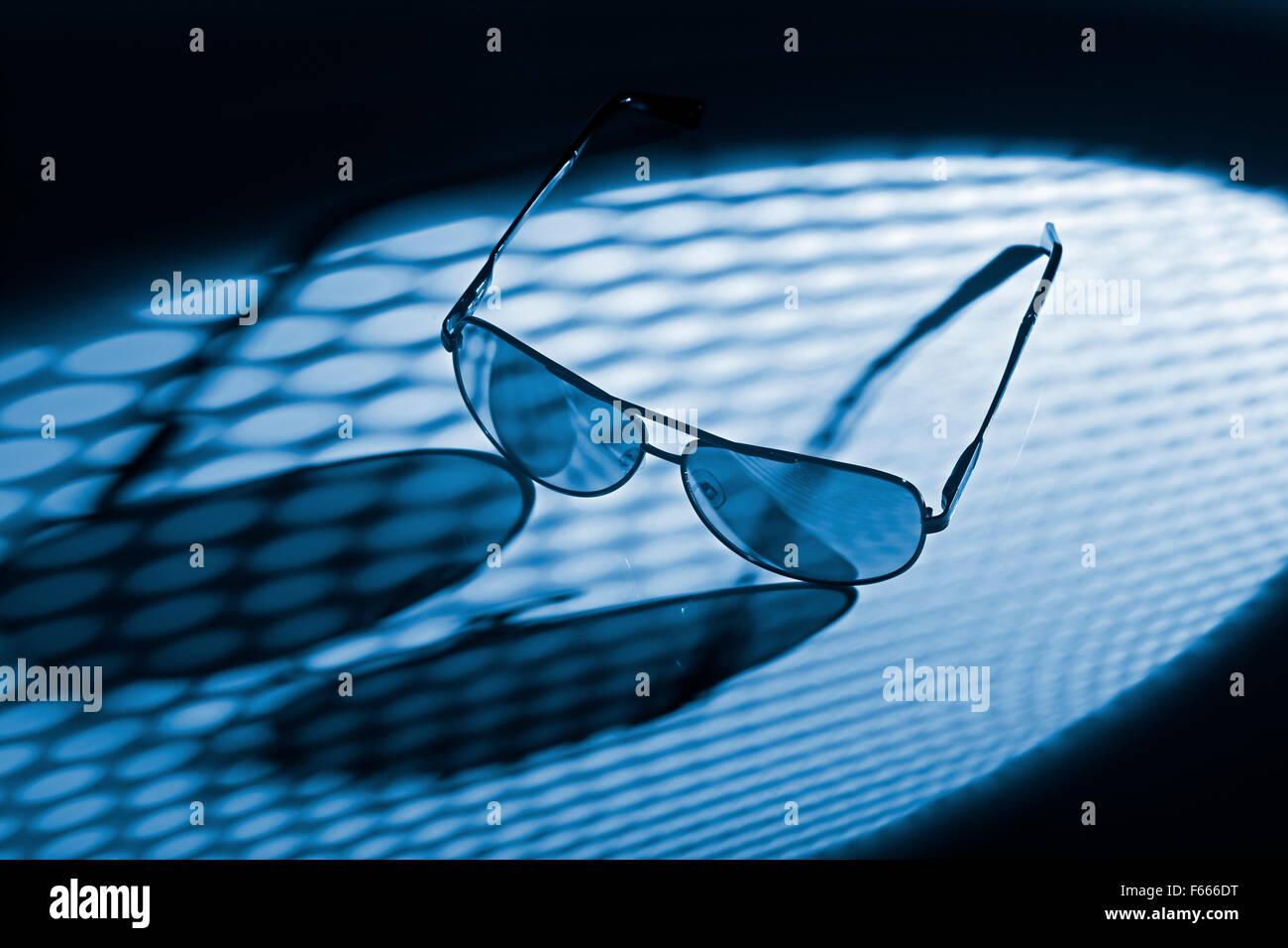 Blue toned photo of sunglasses in dotted light. Stock Photo
