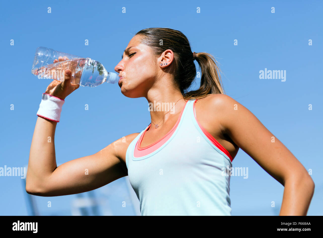 Young beautiful athlete drinking water after exercising to revitalize Stock Photo