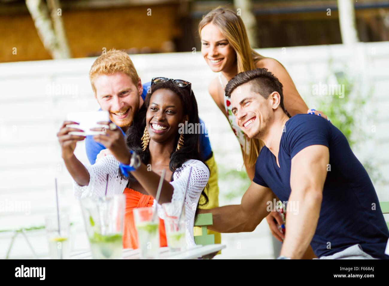 A group of friends sitting a table and talking smiling while taking ...
