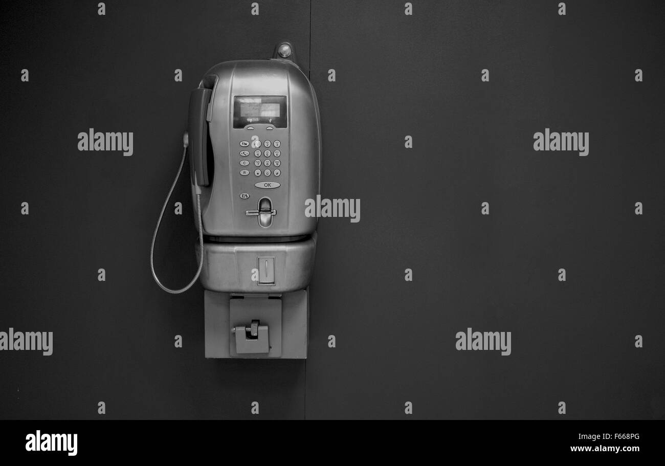 old public phone on a gray wall Stock Photo