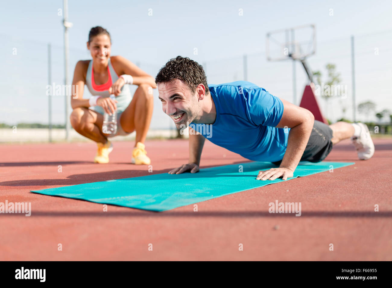 Young, beautiful, fit and healthy personal trainer counting push-ups and motivating Stock Photo