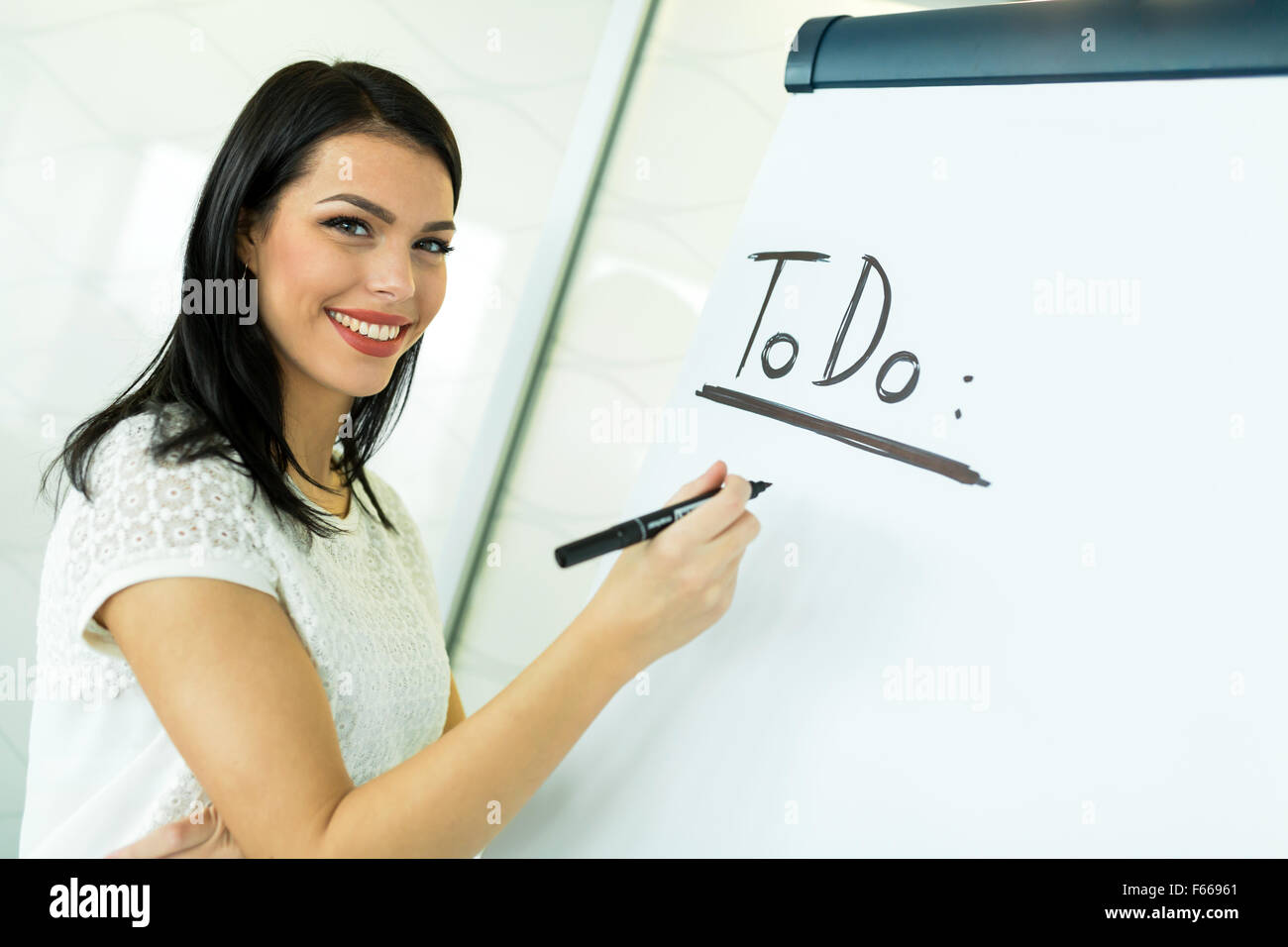 Beautiful, young, businesswoman writing todo onto a white writing board Stock Photo