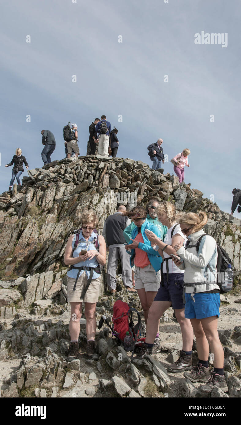 A group of female walkers texting on the summit of Snowdon, Snowdonia National Park, North Wales, UK Stock Photo