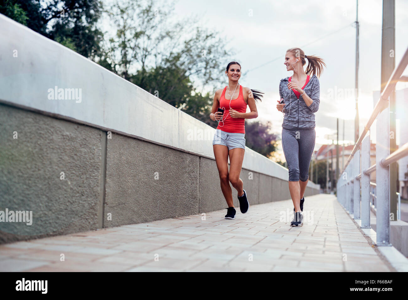 Beautiful scenery of two female joggers pursuing their activity outdoors in the city in dusk Stock Photo