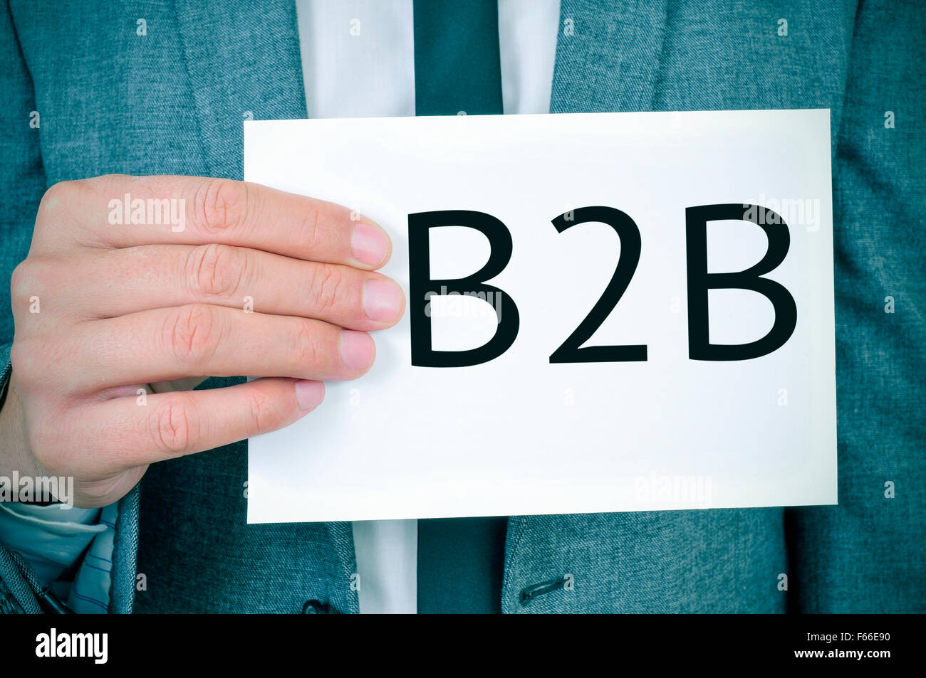 closeup of a young caucasian man in a gray suit showing a signboard with the word B2B written in it Stock Photo