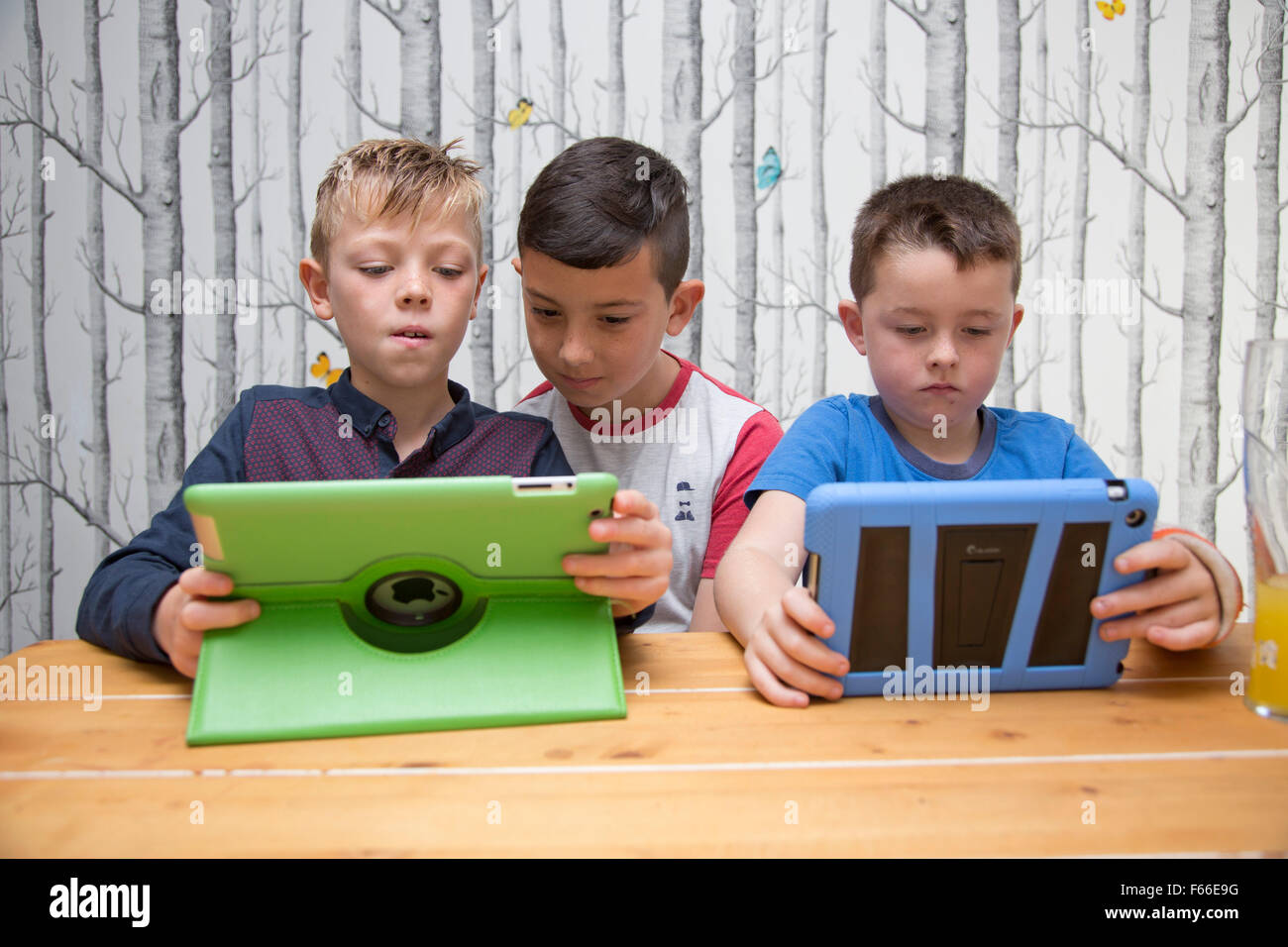 Three young boys playing games on tablets Stock Photo Alamy