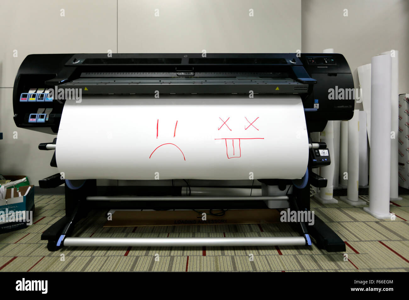 HP L26500 wide-format plotter printer with frowning faces on paper. Stock Photo