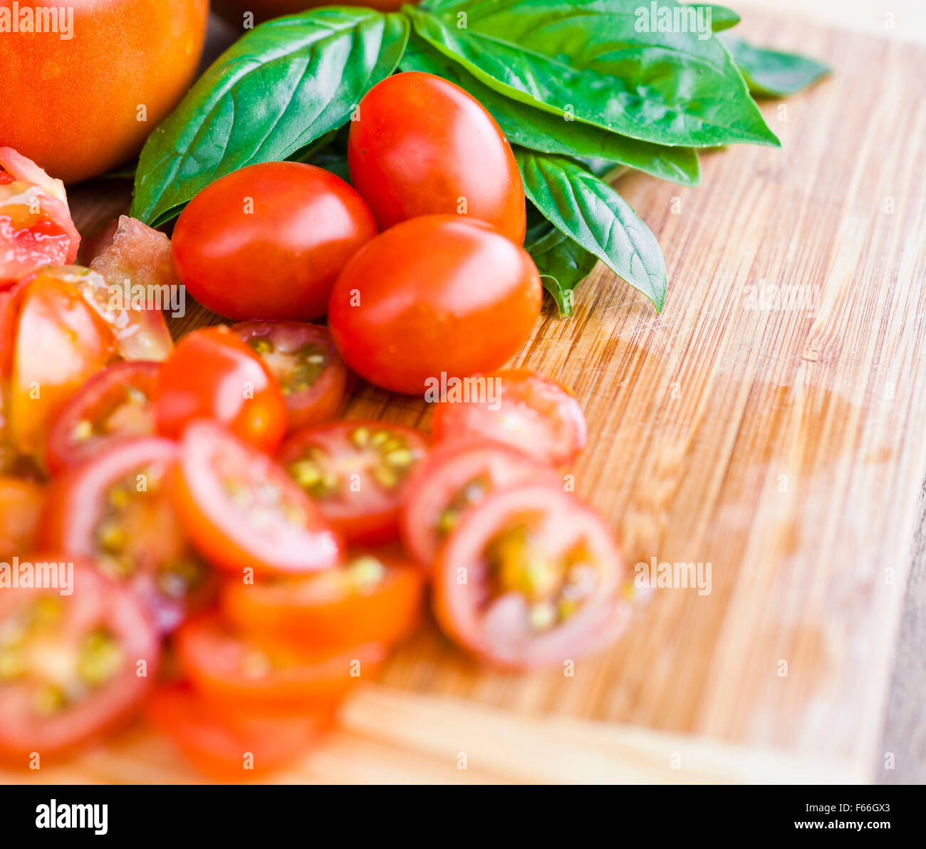 Freshly chopped cherry tomatoes and basil on a chopping board Stock Photo