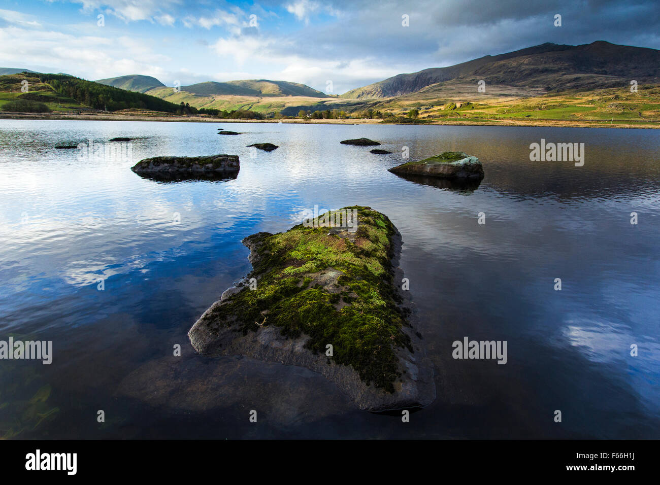 Landscape image of rocks in a lake with mountain backdrop and storm blowing in over Mt Snowdon. Stock Photo