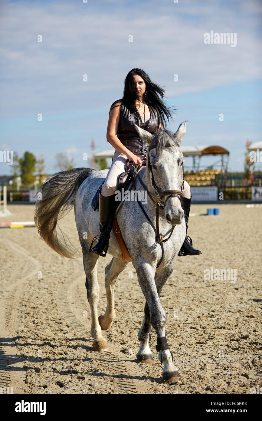 Beautiful young woman riding a horse on a hippodrome Stock Photo