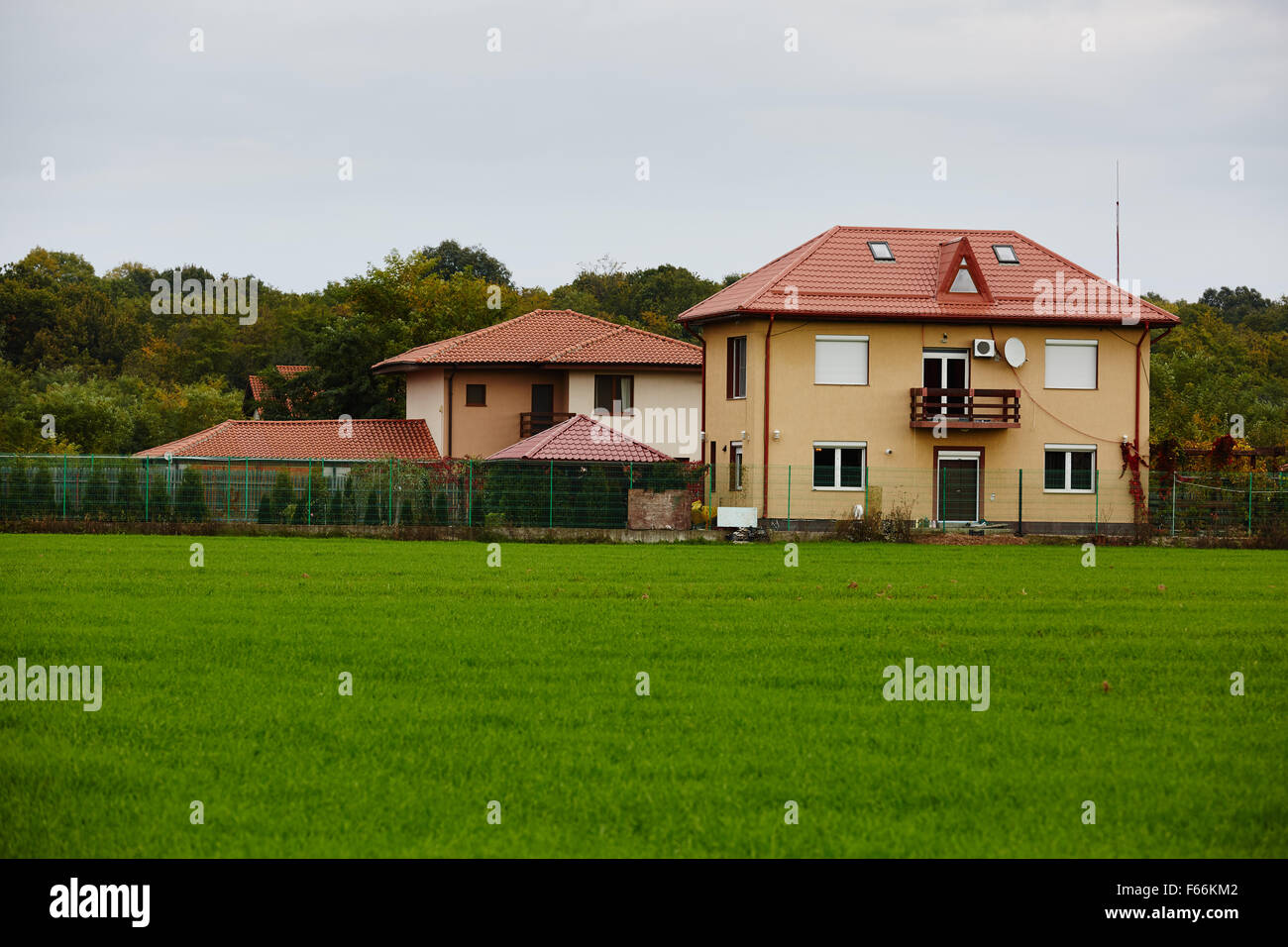 A new house with green grass field in front and forest in the ...