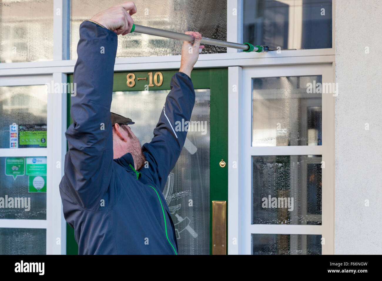 Window cleaning. Window cleaner cleaning windows of a business, Nottingham, England, UK Stock Photo