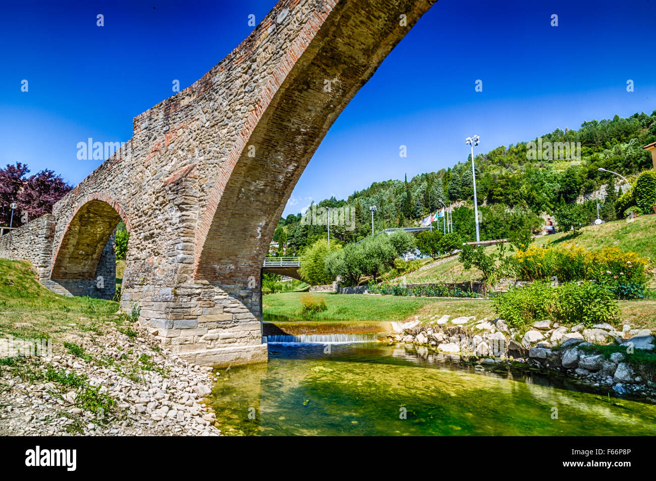 The XVIII century bridge in Modigliana in Italy is overlooking the quiet waters of a small creek with the medieval humpback structure of the three archs Stock Photo
