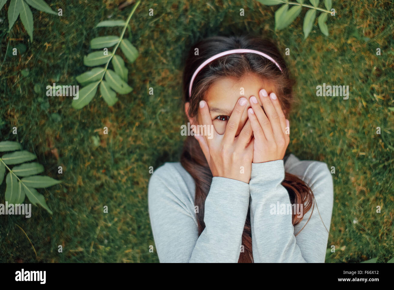 Little girl lying on the grass and laugh. Stock Photo