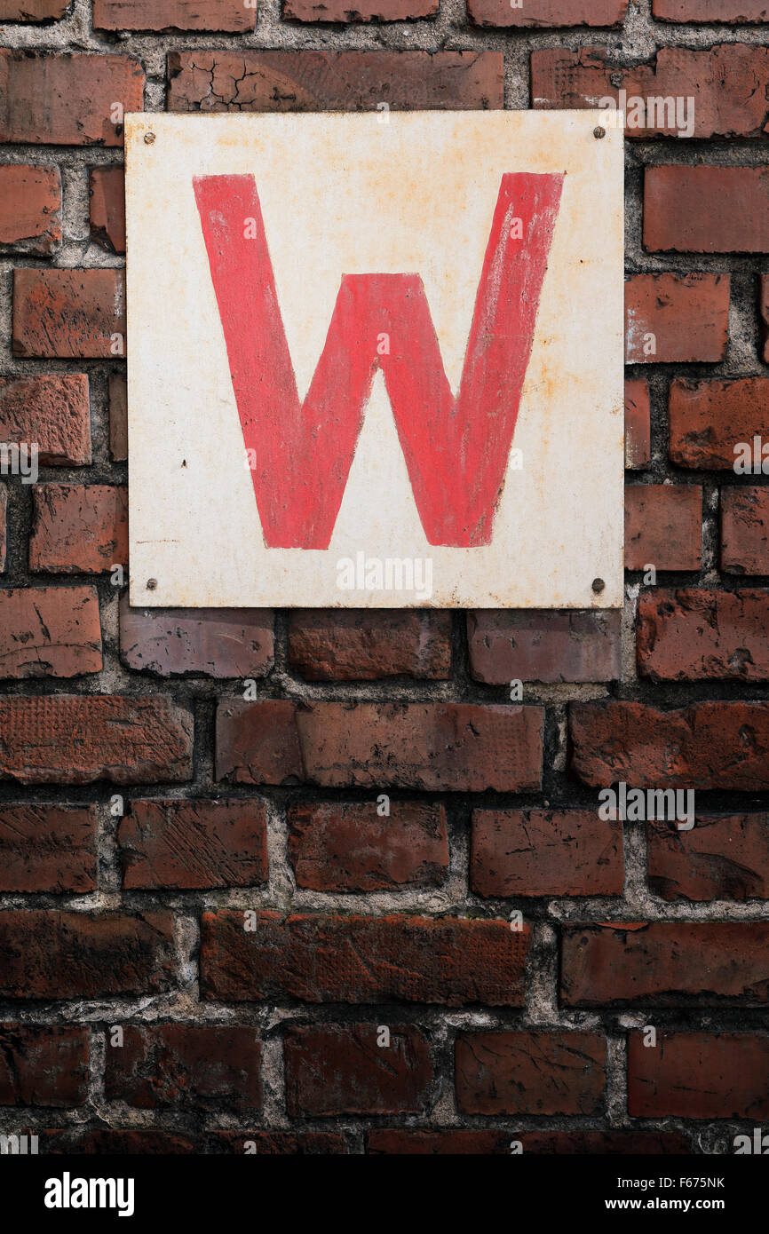 Old sign with letter W on a brick wall. Stock Photo