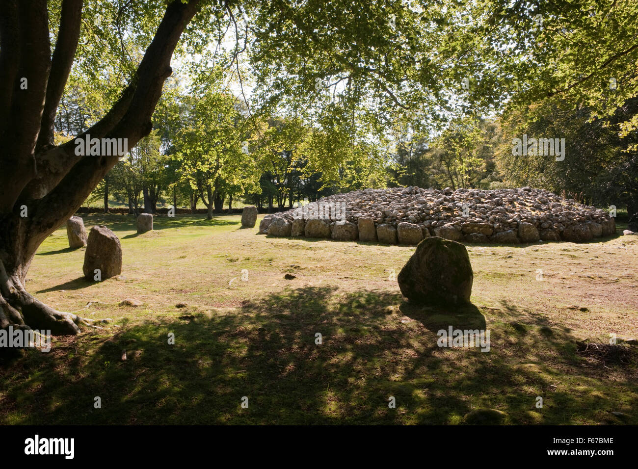 Looking SW at the rear of Clava NE Bronze Age passage grave, Inverness, surrounded by standing stones. One of the kerbstones is covered in cupmarks. Stock Photo