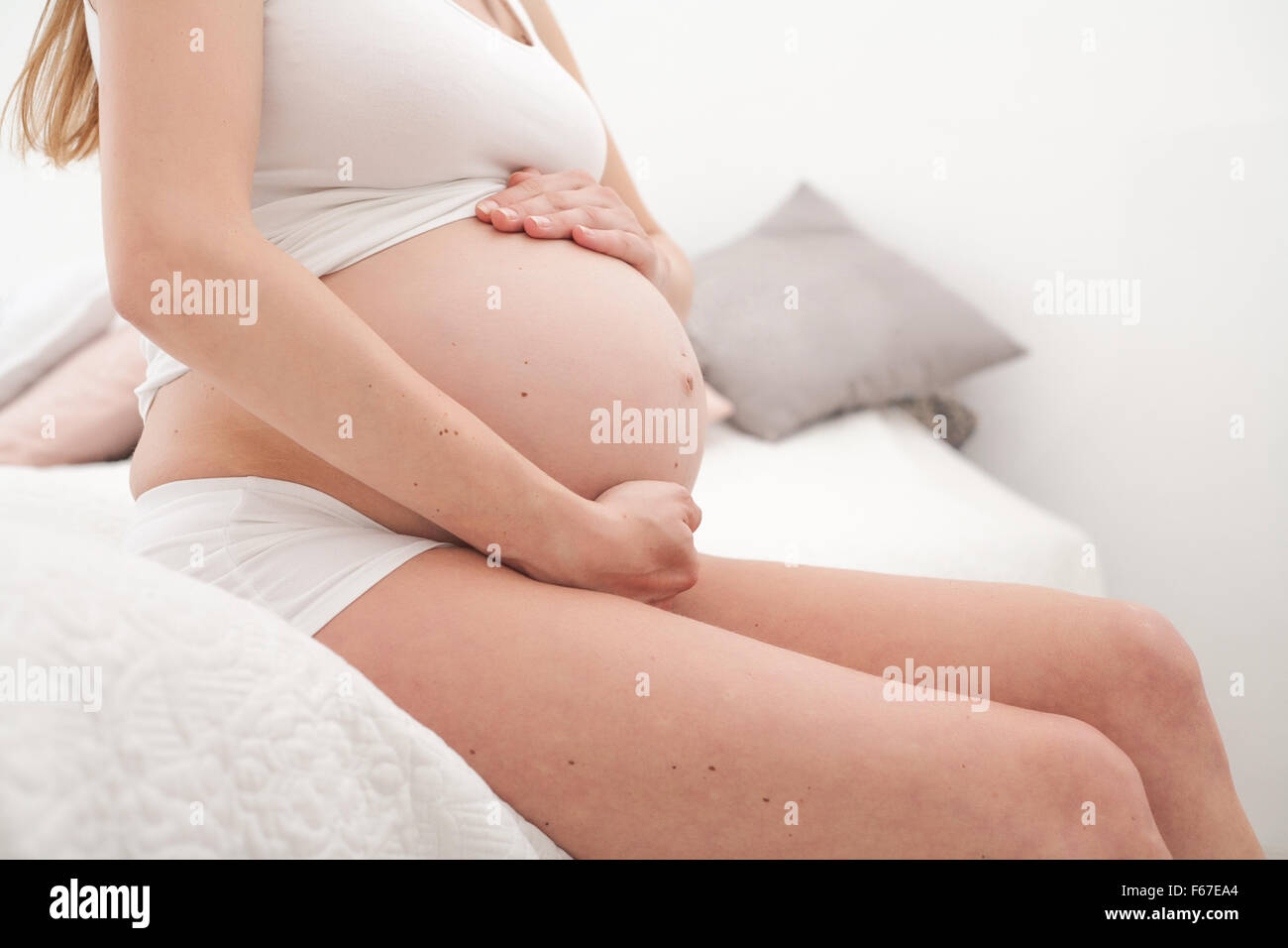 Young new mother is sitting on a bed Stock Photo