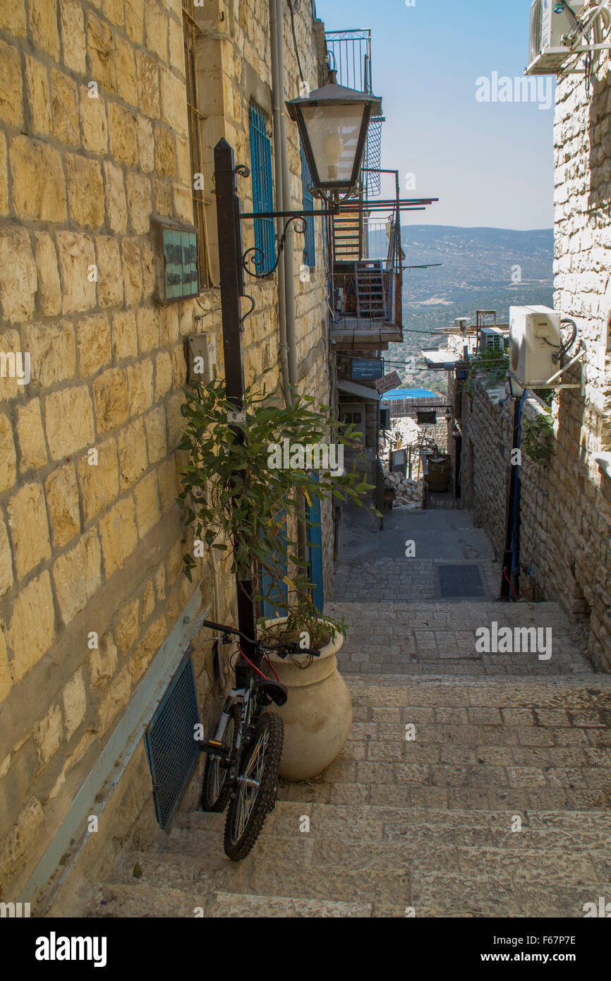 Safed, Israel - Typical street alley in Safed's old city with stone walls and blue coloured doors.View to surrounded mountains Stock Photo