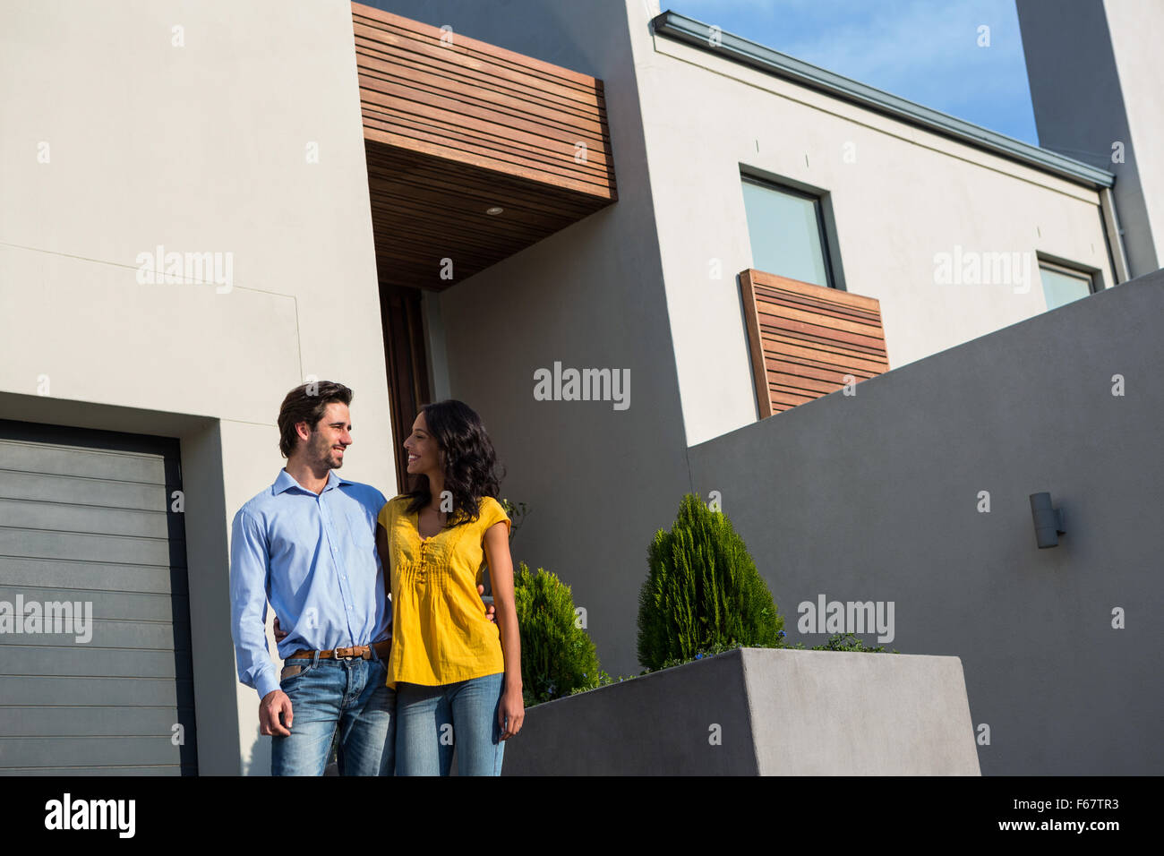 Happy couple standing in front of new house Stock Photo - Alamy