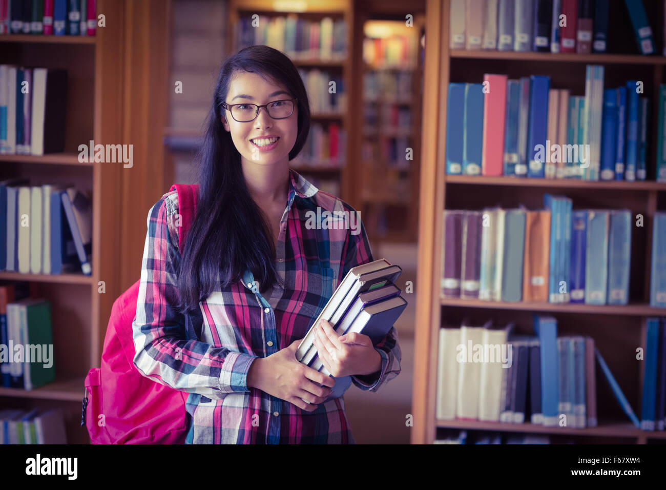 Smiling student holding books in library Stock Photo - Alamy