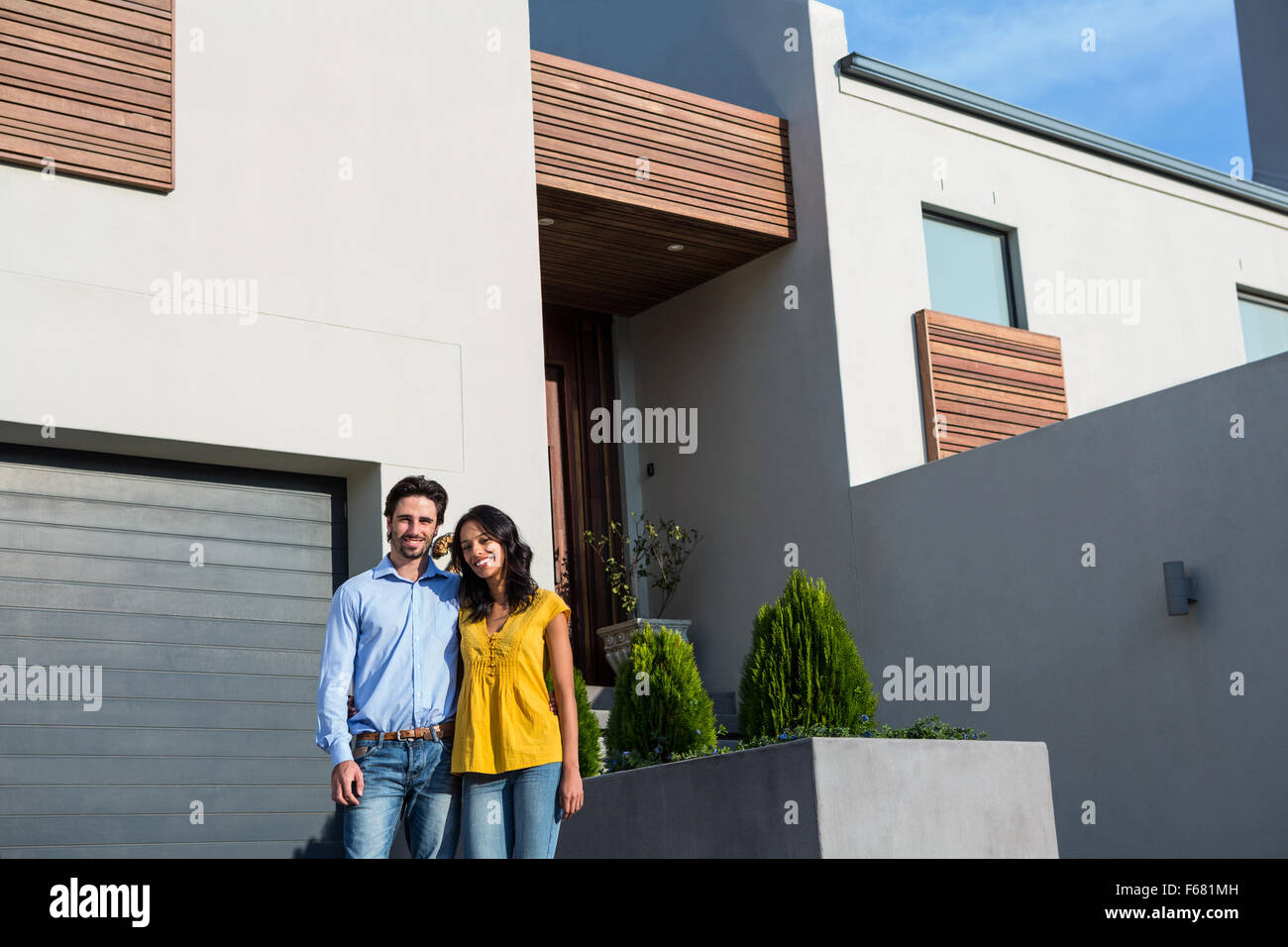 Happy couple standing in front of new house Stock Photo - Alamy