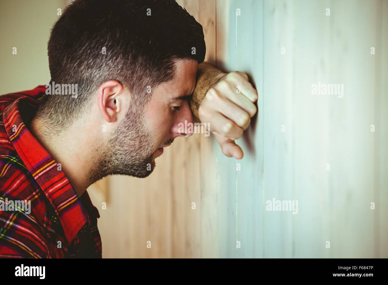 Stressed man leaning against wall Stock Photo