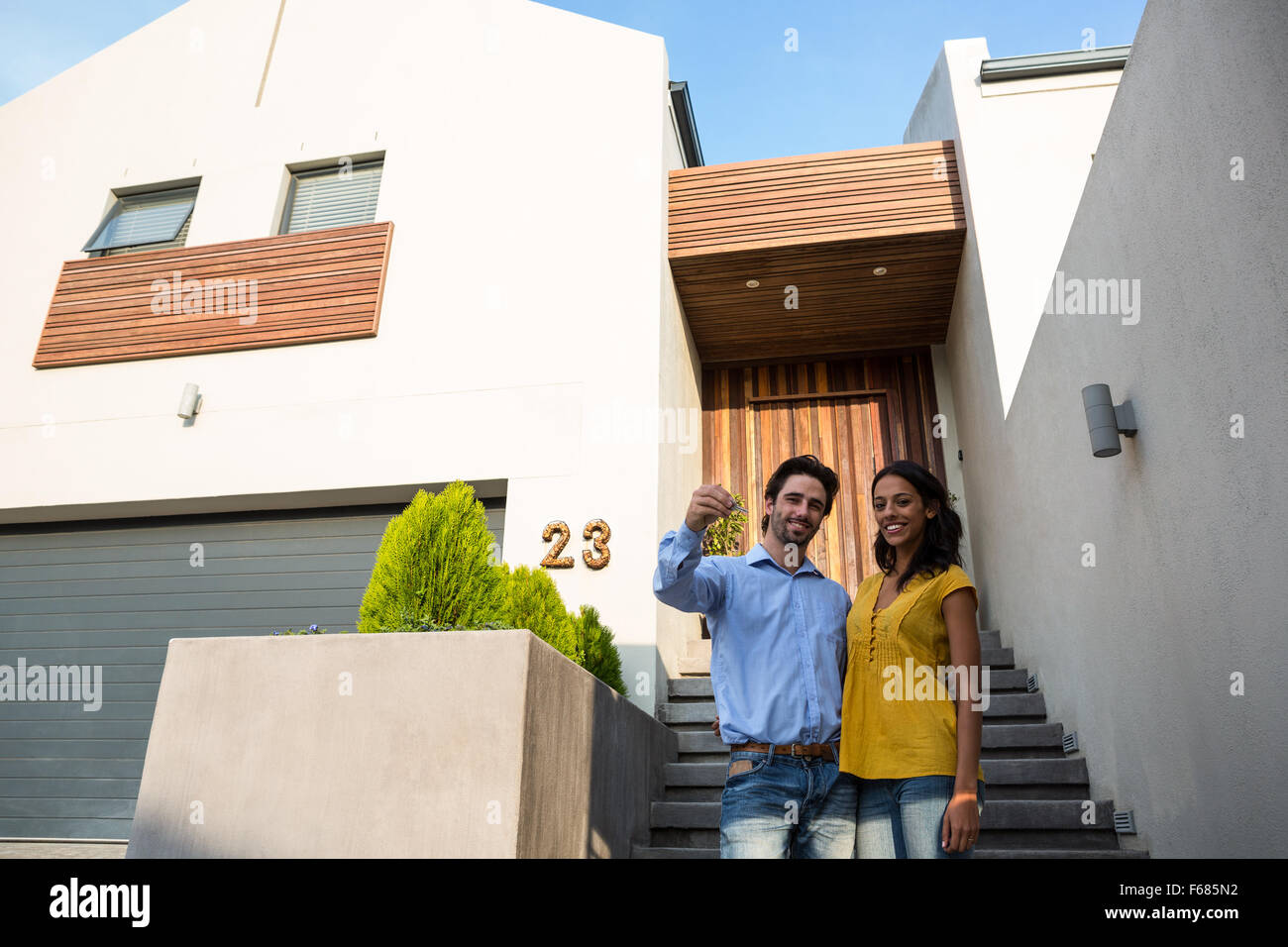Happy couple in front of new house showing keys Stock Photo - Alamy