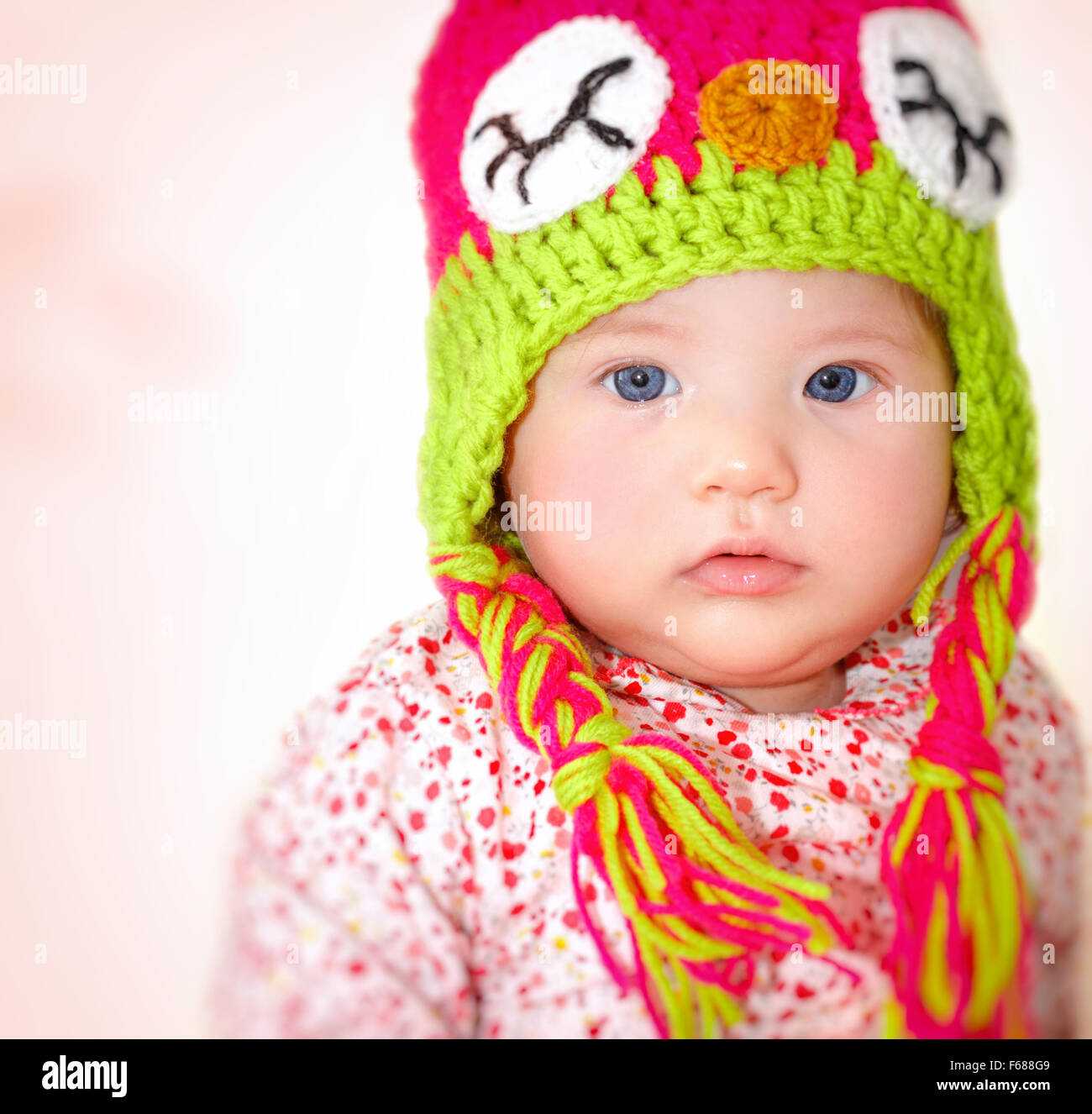 Closeup portrait of adorable child wearing beautiful colorful hat over pink background, cool winter style for little girls Stock Photo