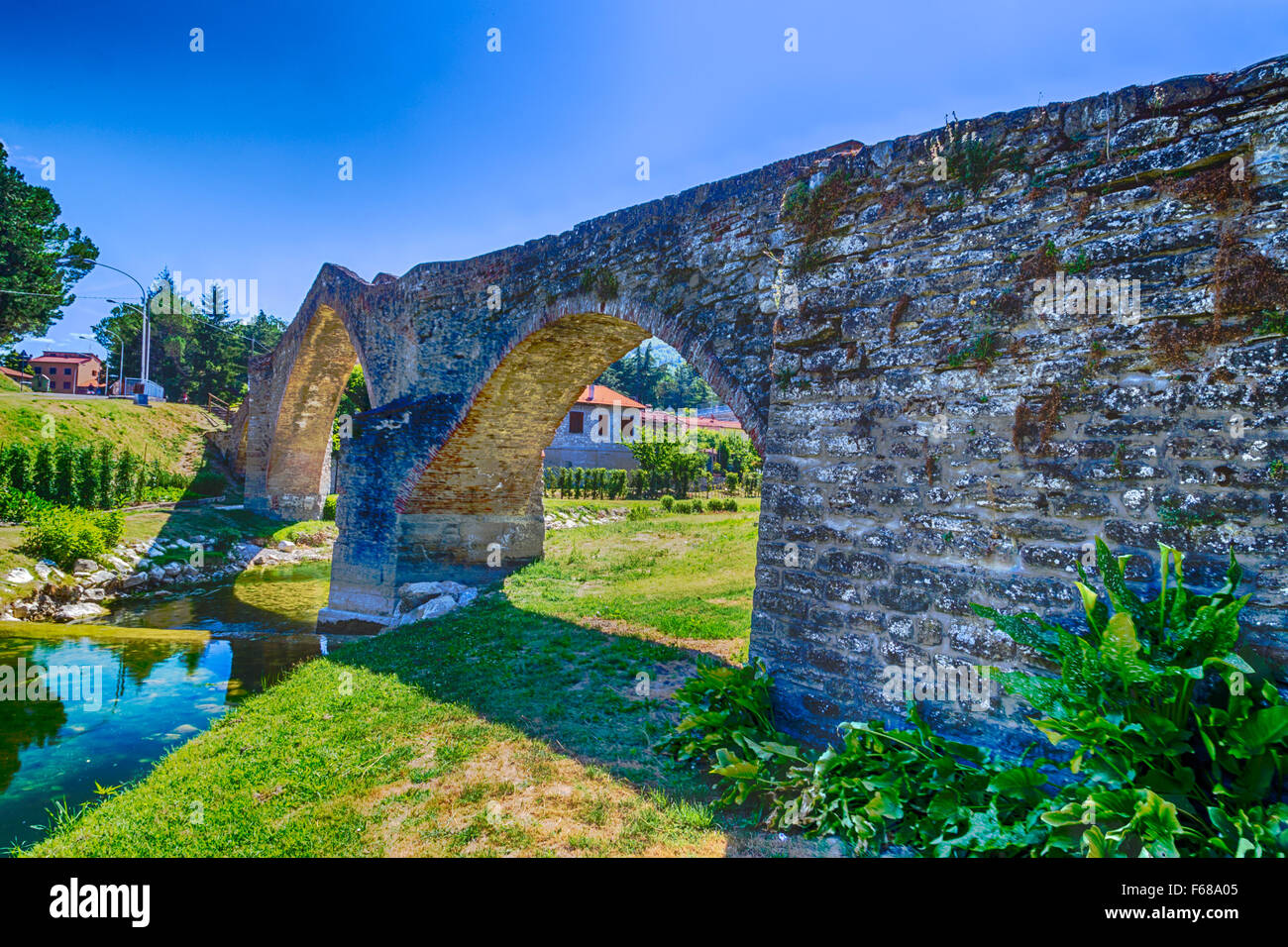 The XVIII century bridge in Modigliana in Italy is overlooking the quiet waters of the small creek with the medieval humpback structure of the three archs Stock Photo