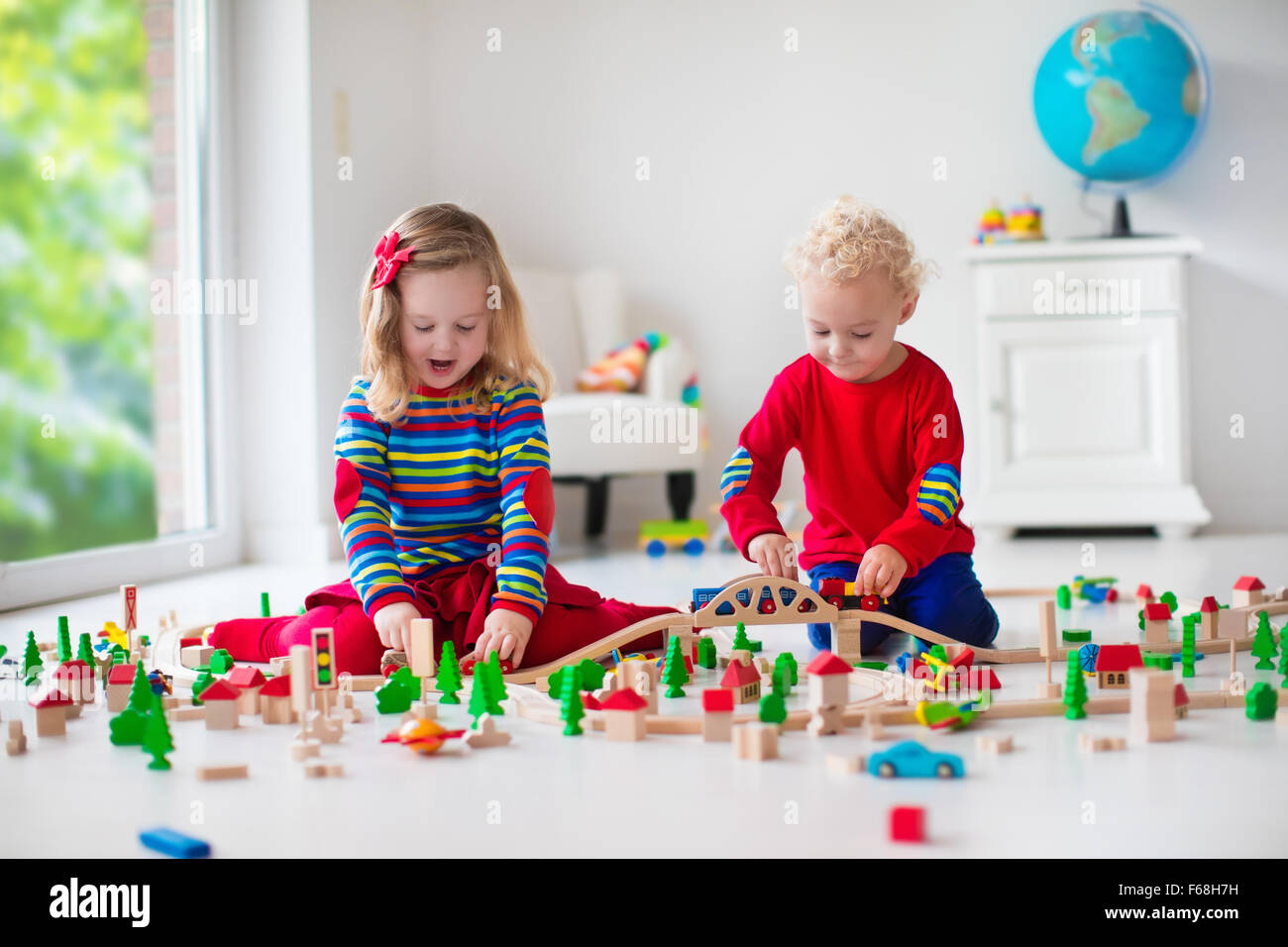 Children playing with wooden train. Toy railroad. Toddler kid and baby
