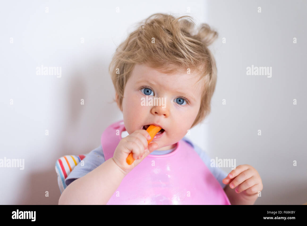 One year old baby eating a healthy carrots and vegetables Stock Photo