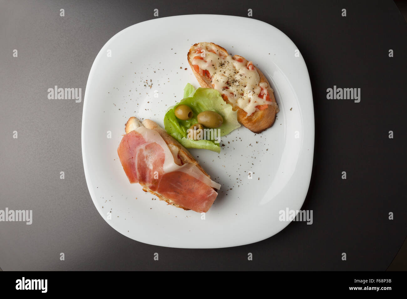 sandwiches, baked with prosciutto and cheese on white plate Stock Photo
