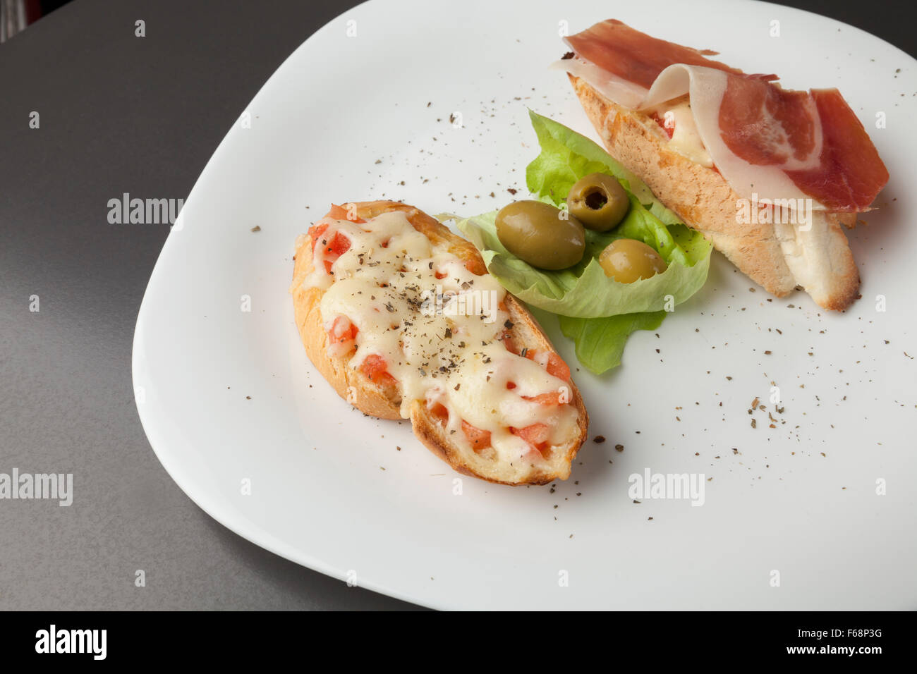 sandwiches, baked with prosciutto and cheese on white plate Stock Photo