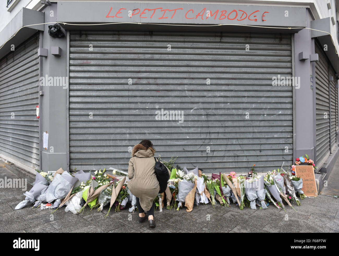 Paris, France. 14th Nov, 2015. A woman lays flowers outside the Le Petit Cambodge bar in Rue Alibert in Paris, France, 14 November 2015. At least 120 people have been killed in a series of terrorist attacks in Paris. PHOTO: UWE ANSPACH/DPA/Alamy Live News Stock Photo