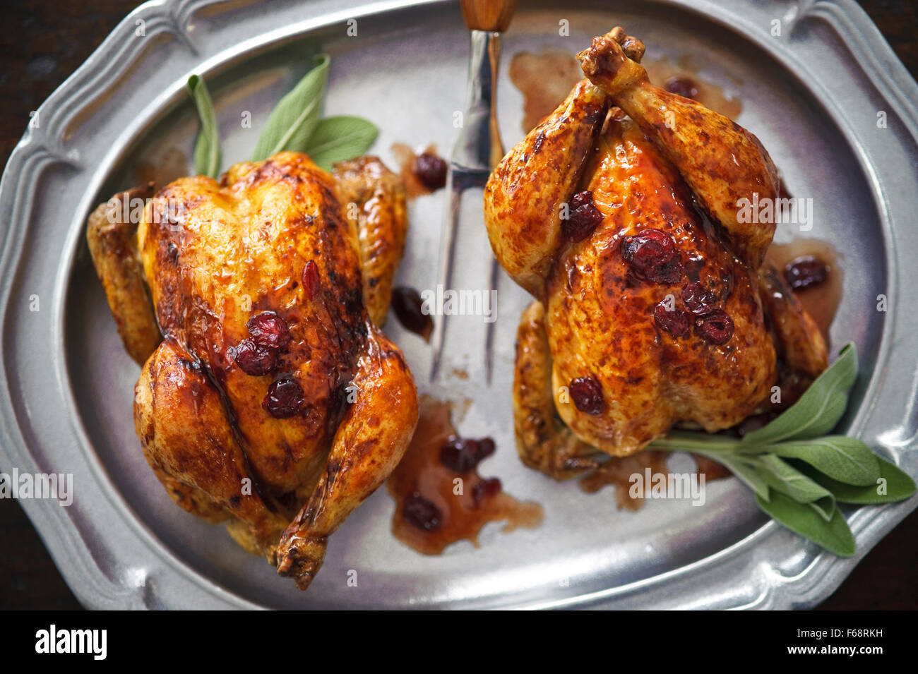 Pair of Cornish game hens roasted in cranberry sauce. Stock Photo